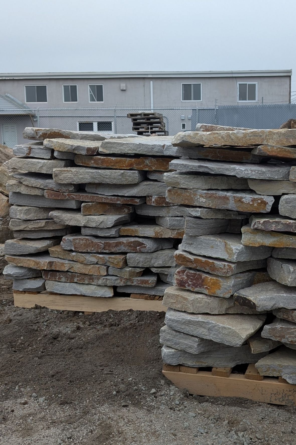 Piles de pierres plates empilées sur palettes dans une zone extérieure  à Beloeil
