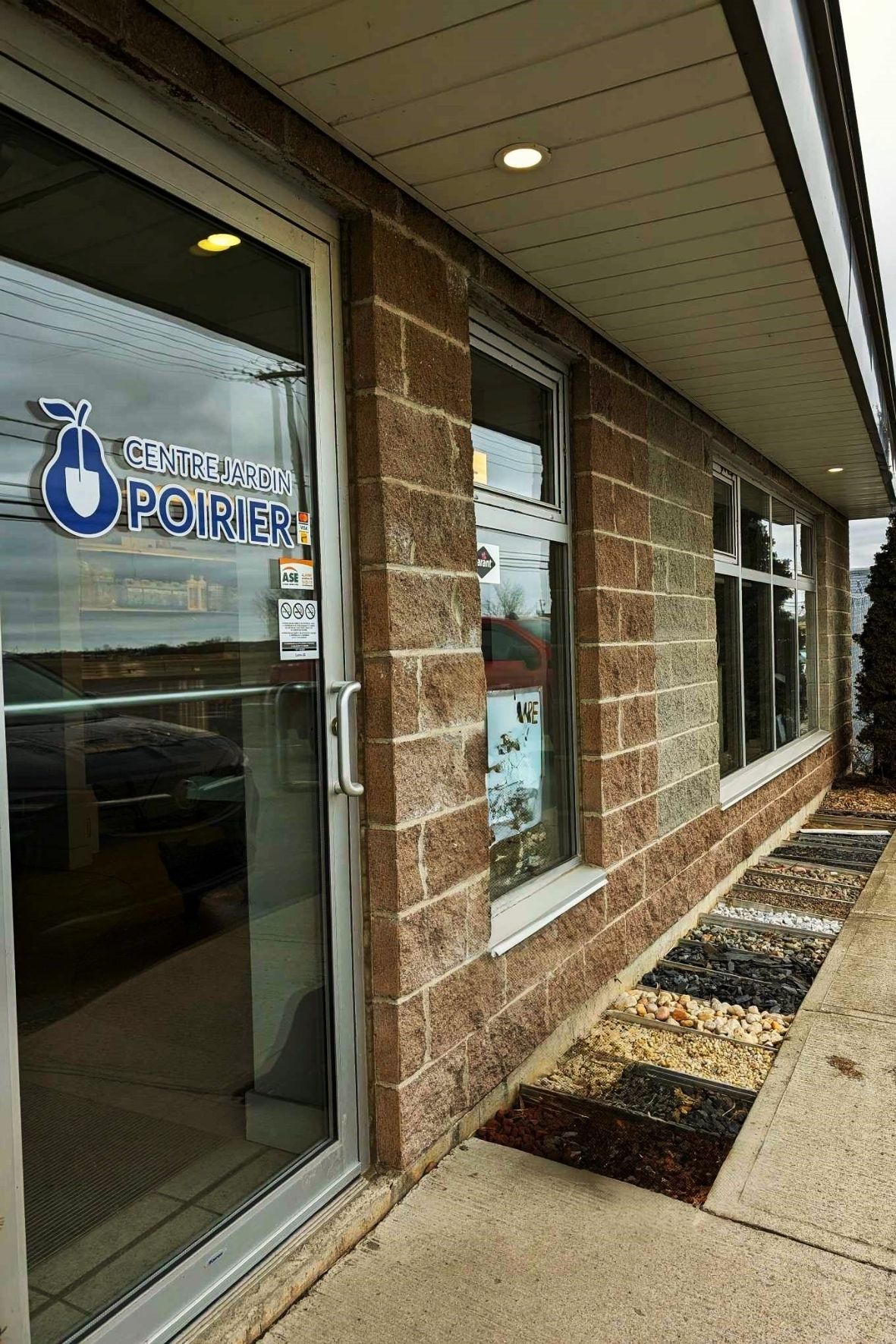 Entrée de bâtiment avec vitrine et bacs de matériaux décoratifs au sol  à Chambly