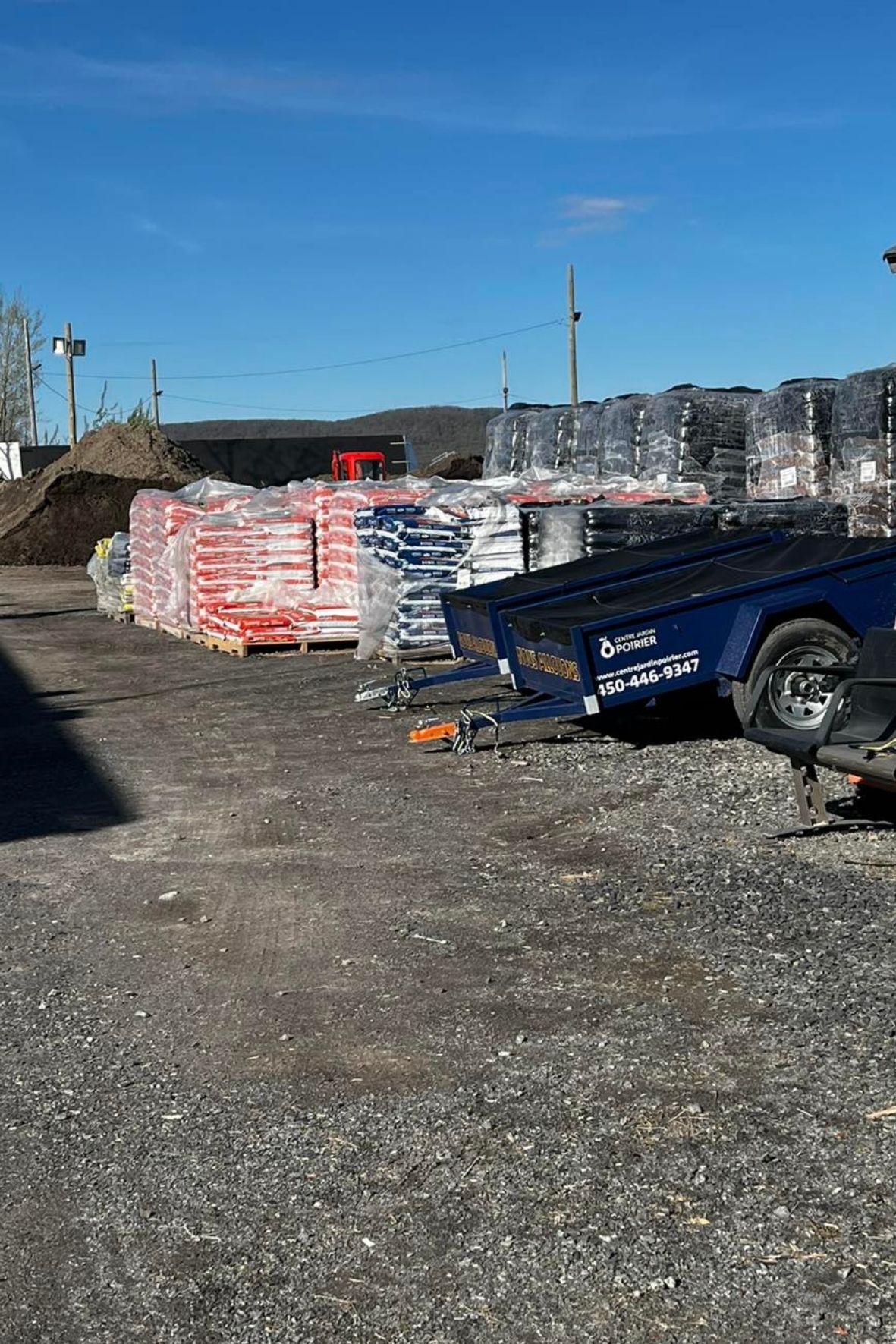 Cour extérieure avec palettes de sacs, remorque et matériaux entreposés  à Saint-Jean-Baptiste