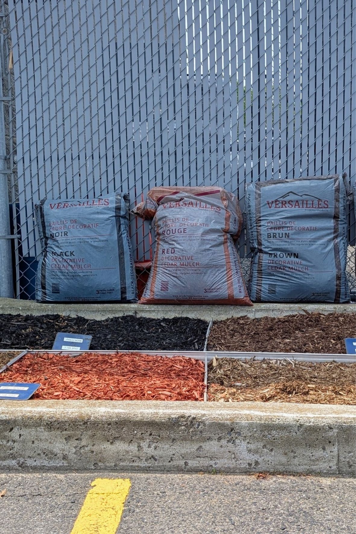 Sacs de paillis et matériaux paysagers exposés le long d’une clôture  à Saint-Marc-sur-Richelieu